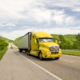 yellow semi truck travels on interstate in springtime SYv1z06No