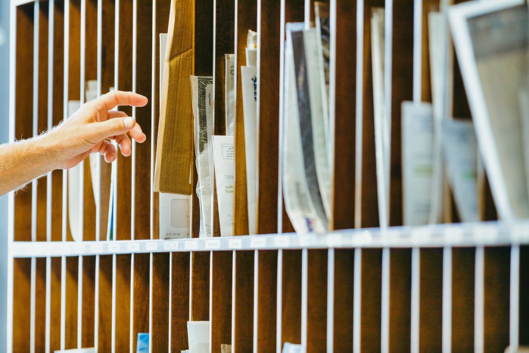 hand reaches into wooden mail organizer, selecting
