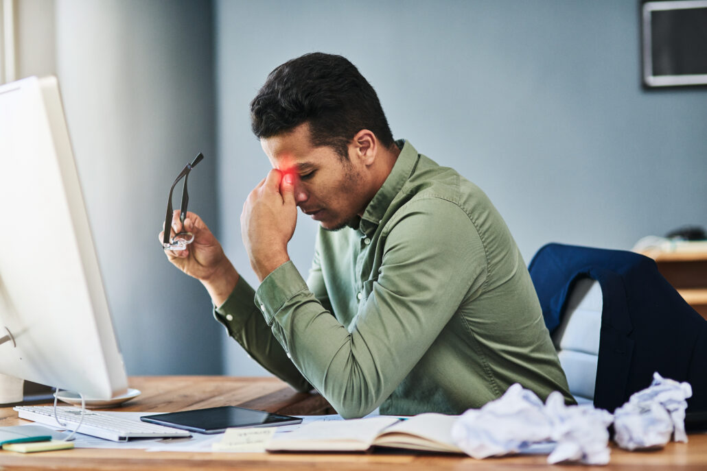 man, stress and headache in office by computer with glass, pain or red glow with chaos at company. business person, tired and fatigue with migraine, exhausted and burnout with mess by pc at workplace
